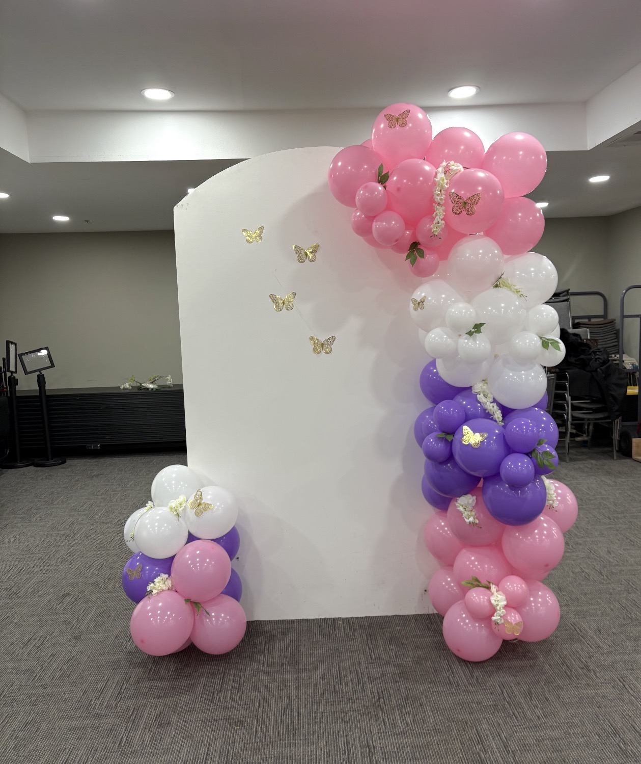 Pink, purple and white balloon arch backdrop with gold butterflies